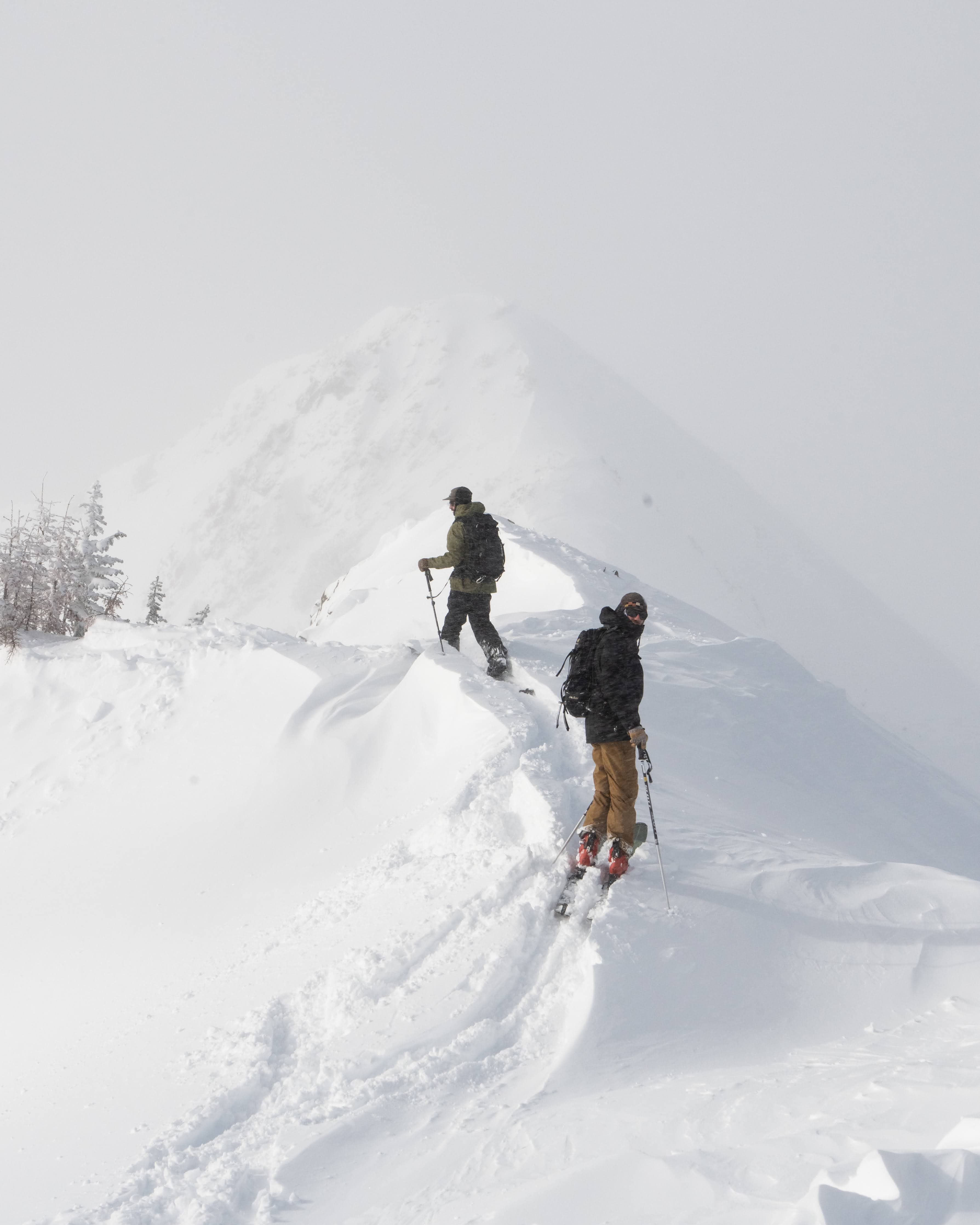 Skiers climbing a snowy ridge above the property.